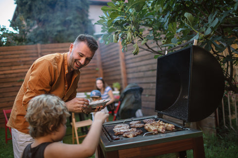 Father cooking BBQ with his son in back yard