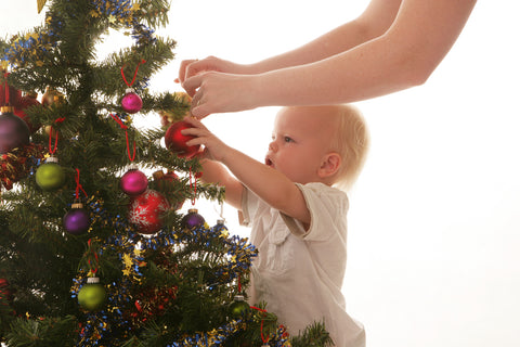 Image of a toddler and his mother decorating a Christmas Tree