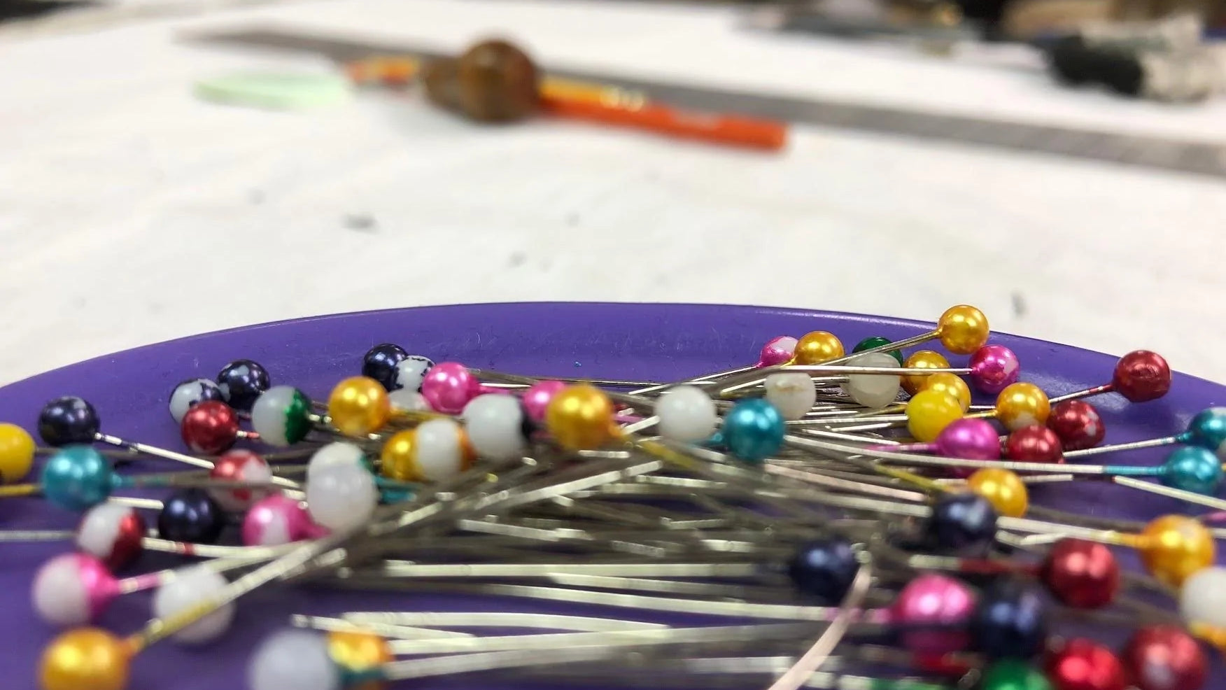 A collection of sewing pins on a purple dish.