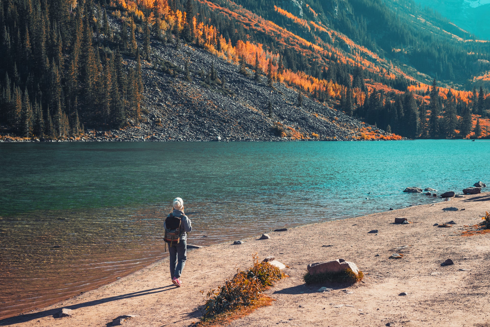woman hiking next to a lake and mountains