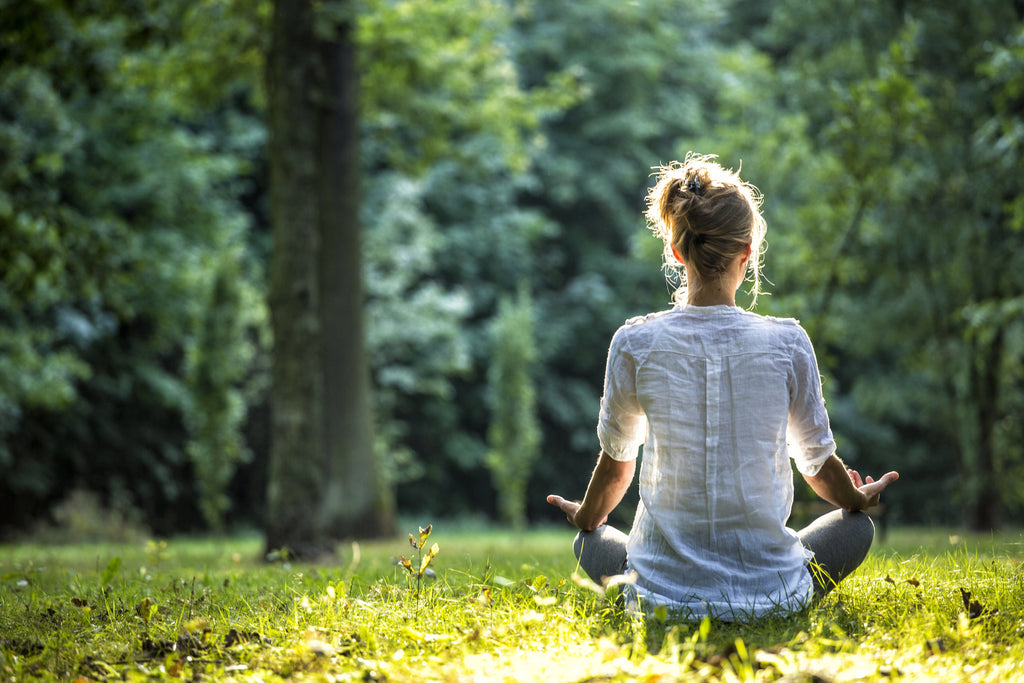 woman meditating in the woods at sundown