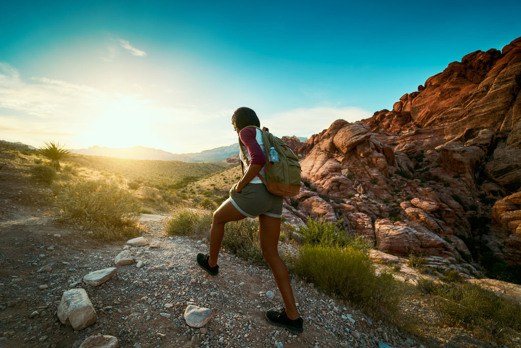 a woman hiking on a trail at sunset