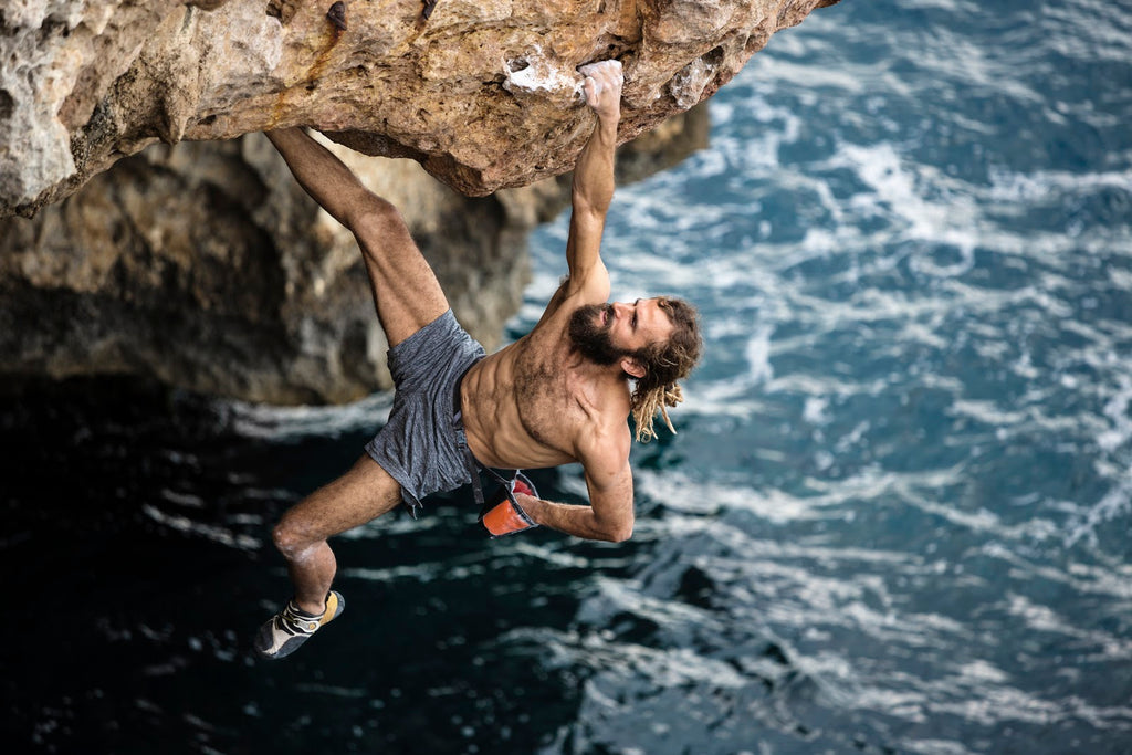 man free soloing in a cliff by the ocean