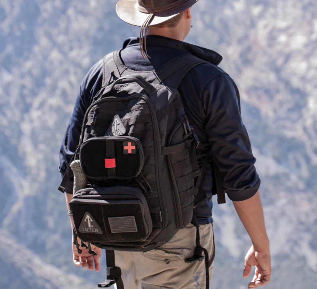 A hiker using a tactical backpack configured with added external pouches. The 14er Tactical Backpack has a MOLLE system that supports this kind of handy customization.