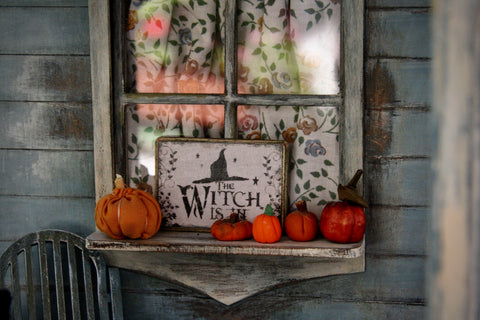 Halloween sign and pumpkins on window shelf