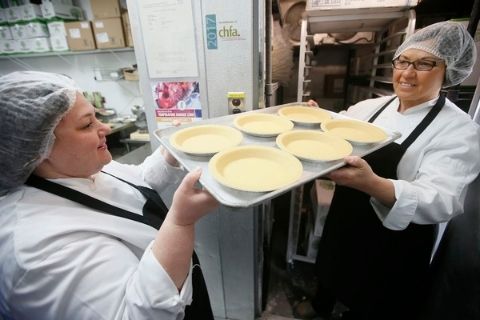 Prairie food producers, Piccola Cucina, in a league of their own. Pina (left) and Anita (right) holding a tray of almond crust pie shells in their manufacturing facility in Winnipeg