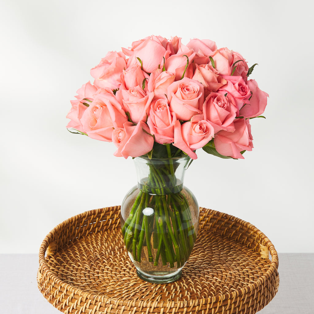 pink roses in a vase on a rattan tray