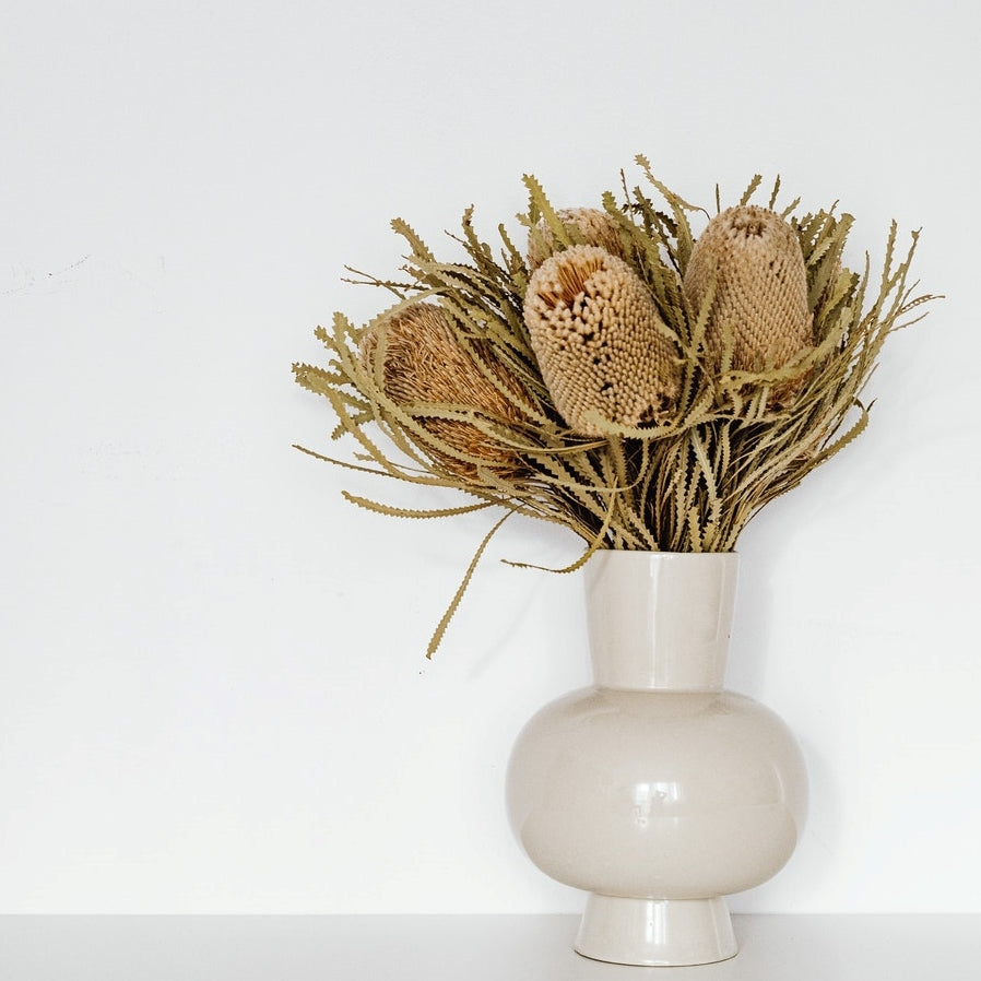 dried banskia and grasses in a white ceramic vase