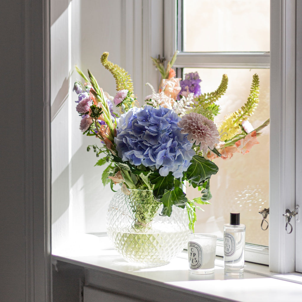 flowers in a vase on a windowsill in the sun