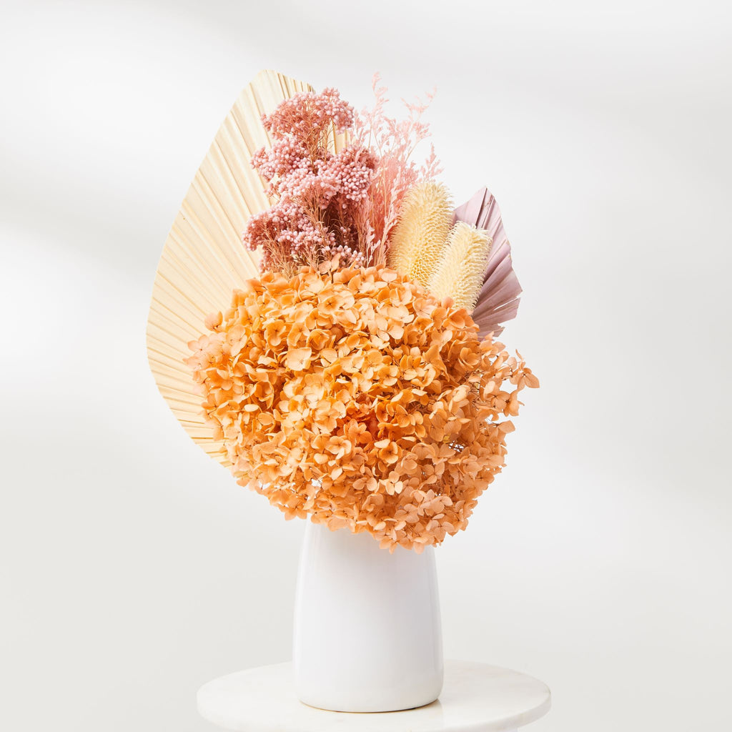 The Talula Dried Flower bouquet, caramel hydrangeas, palm spears, pink dried flowers in a white ceramic vase