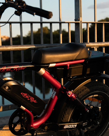 An Ariel Rider Grizzly ebike navigates a vibrant cityscape, highlighting its sleek, motorcycle-like design. This image exemplifies the seamless integration of advanced ebike technology into urban life, catering to those seeking an efficient, stylish, and eco-friendly mode of transportation in the city.