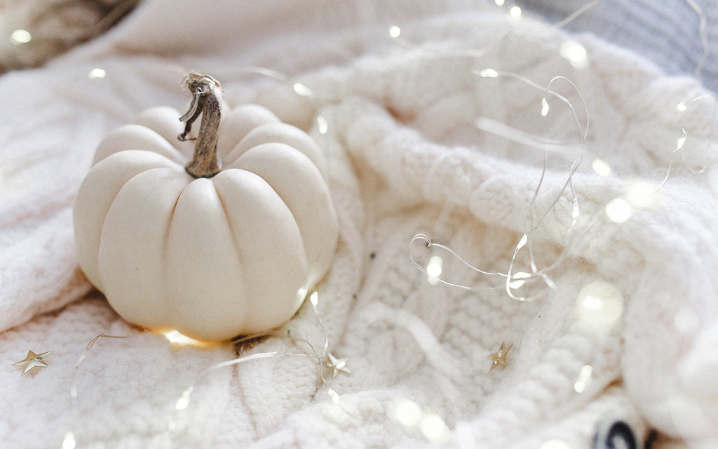 White pumpkin surrounded by string lights 