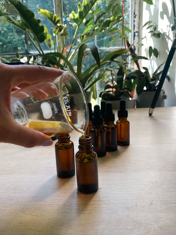 image showing Bous subscription box getting made up, showing Sundrenched essential oil mix being poured in the glass amber dropper bottles 