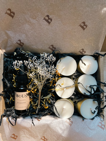 image showing Bous subscription box, containing Sundrenched essential oil mix in dropper bottle.  6 plain soy tealights, a dried flower posy