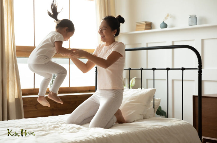 Mother holding hands little daughter in bed