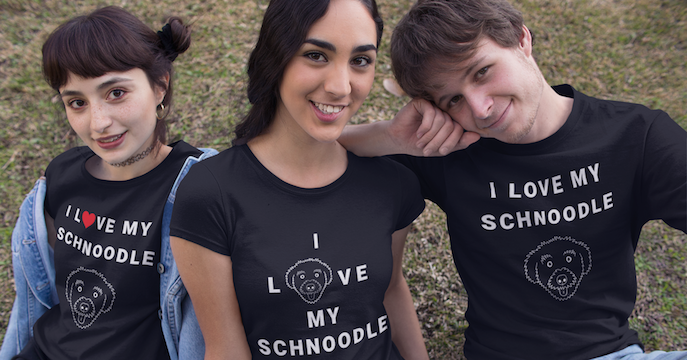 One man and two women posing for a photo wearing T-Shirts from the "I love my schnoodle" collection at The Schnoodle Show.