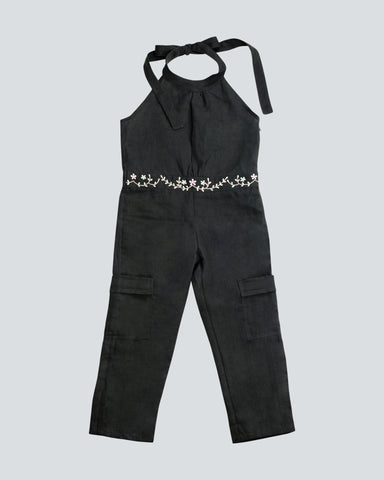Dark Grey linen one piece long leg length jumpsuit with a halter top and tie fastener behind the neck, and a waist band of embroidered pink and white flowers all around front and back of the waistband.