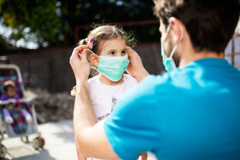 Father putting mask on daughter, Getty Image, How to enjoy the holidays with COVID