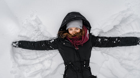 Woman making snow angels in snow.