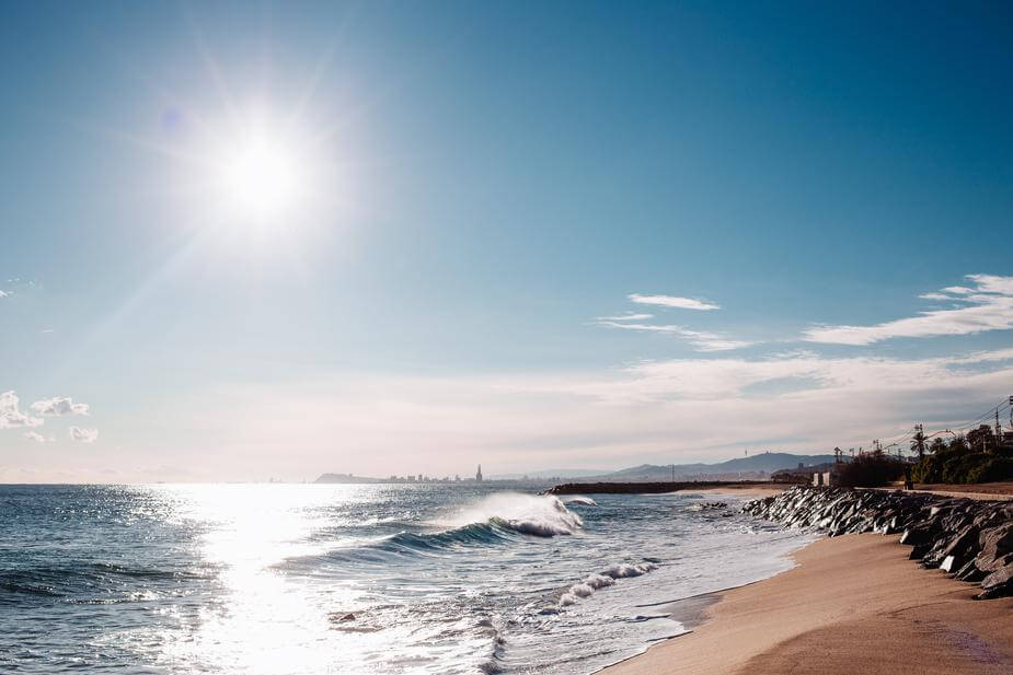 Sun shining over gentle waves that are breaking on a sandy beach