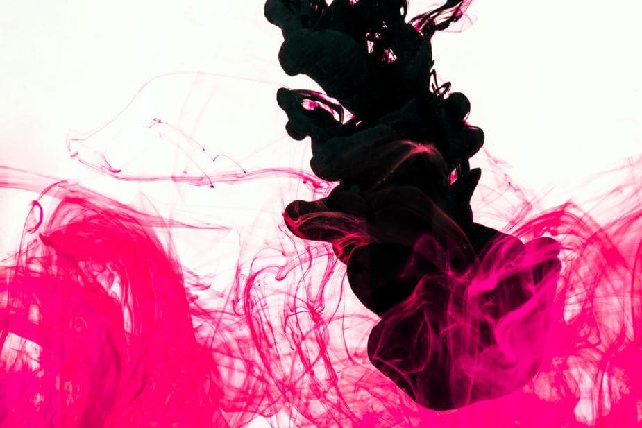 A jet of black ink mixes together with thin wisps of pink ink