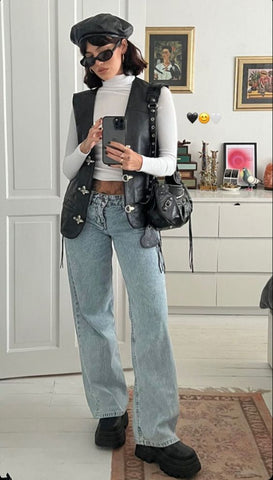 a woman taking a mirror selfie wearing baggy denim, a white long sleeve shirt and a black vest
