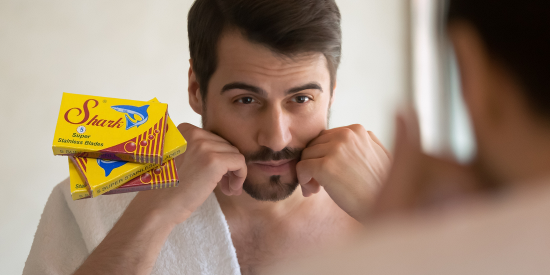 A man stroking his beard after shaving with Shark double-edge blade sin the forefront - Shoreline Shaving