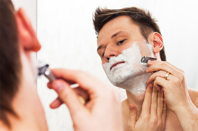 Man shaving with a safety razor from a traditional men's shaving kit - Shoreline Shaving