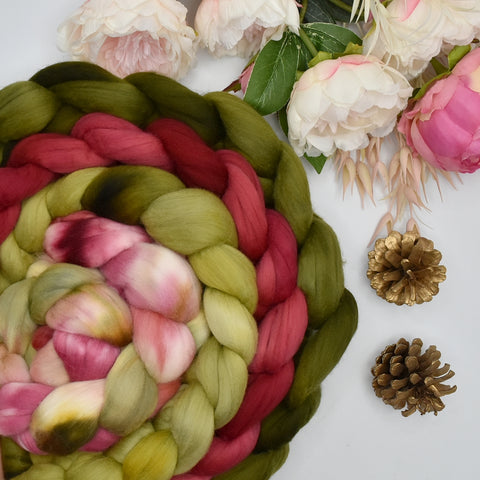 4 braids of christmas inspired coloured Tasmanian merino woo tops rolled up into a circle with flowers and pine cones