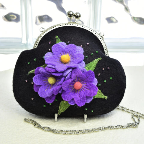 black evening bag hand made from wool felt with a silver clasp and chain with purple flowers on the front.