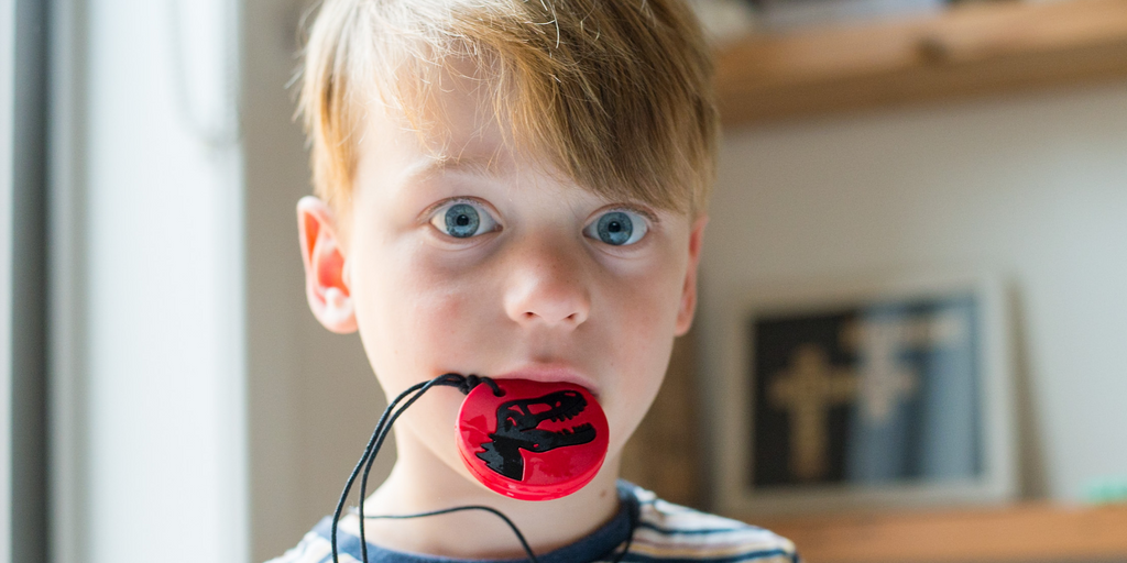 Boy Chewing on Dino Pendant