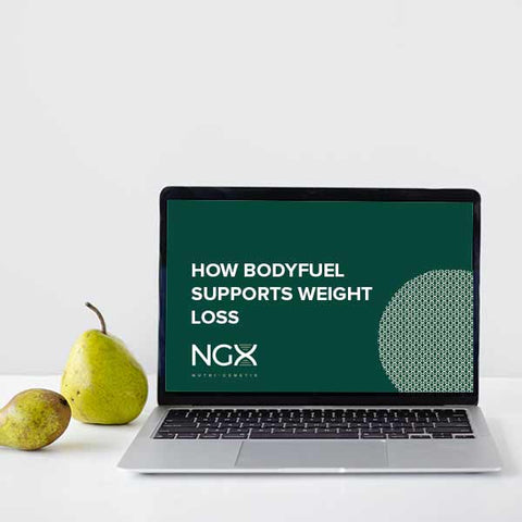 A white desk with a pear standing up next to a laptop which says "How BodyFuel supports weight loss"