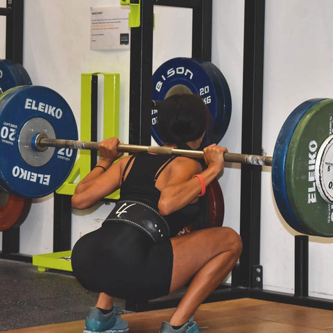 Female squatting with a weightlifting bar.