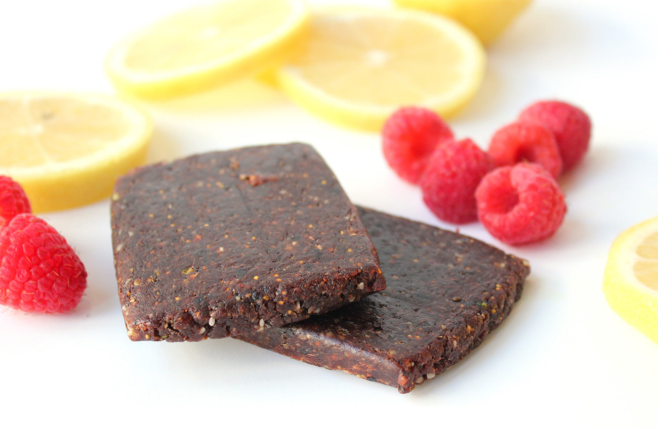 Chocolate energy bars with raspberries and lemon slices on white background
