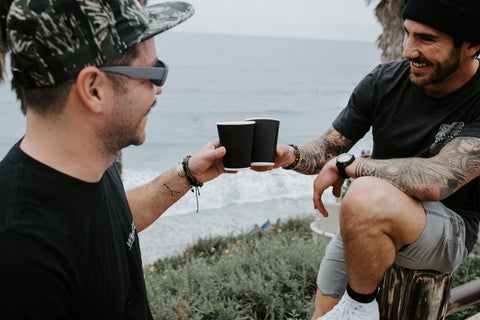 two men enjoying cbd coffee on beach