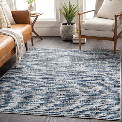 light blue and grey solid rug under a brown leather couch and white chair. 