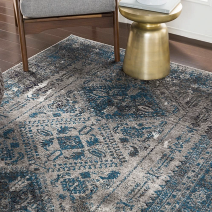 blue and grey tribal rug close up with gold side tabel and chair feet.