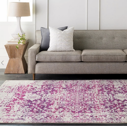 pink tribal rug at the foot of a tan sofa. 