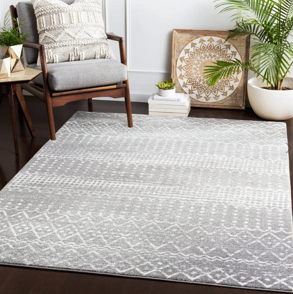 light grey rug on the floor with a palm tree and mid century modern chair in the corner