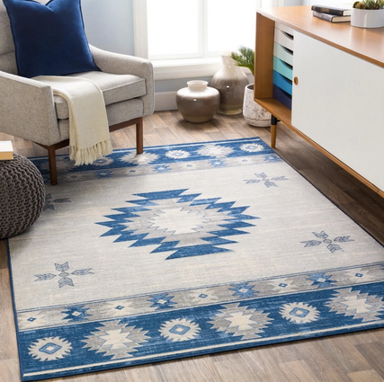 blue and ivory native american printed rug on the floor next to a white chair and white buffet table.
