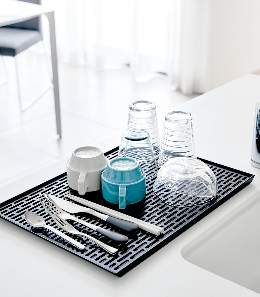 View 7 - Black Dish Drainer Tray holding dishware on sink countertop by Yamazaki Home.