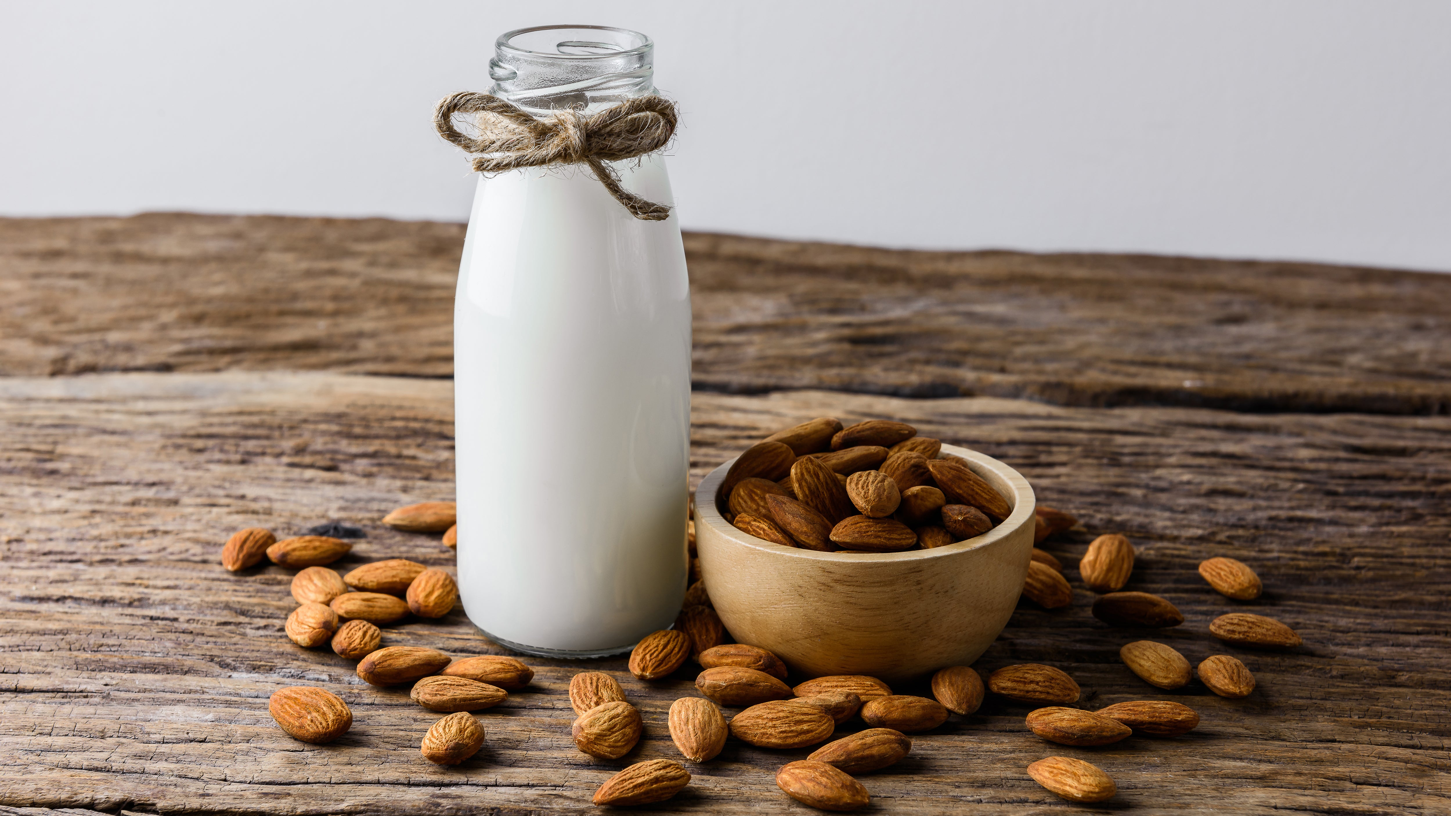 glass container filled with almond milk and a bowl of raw almonds