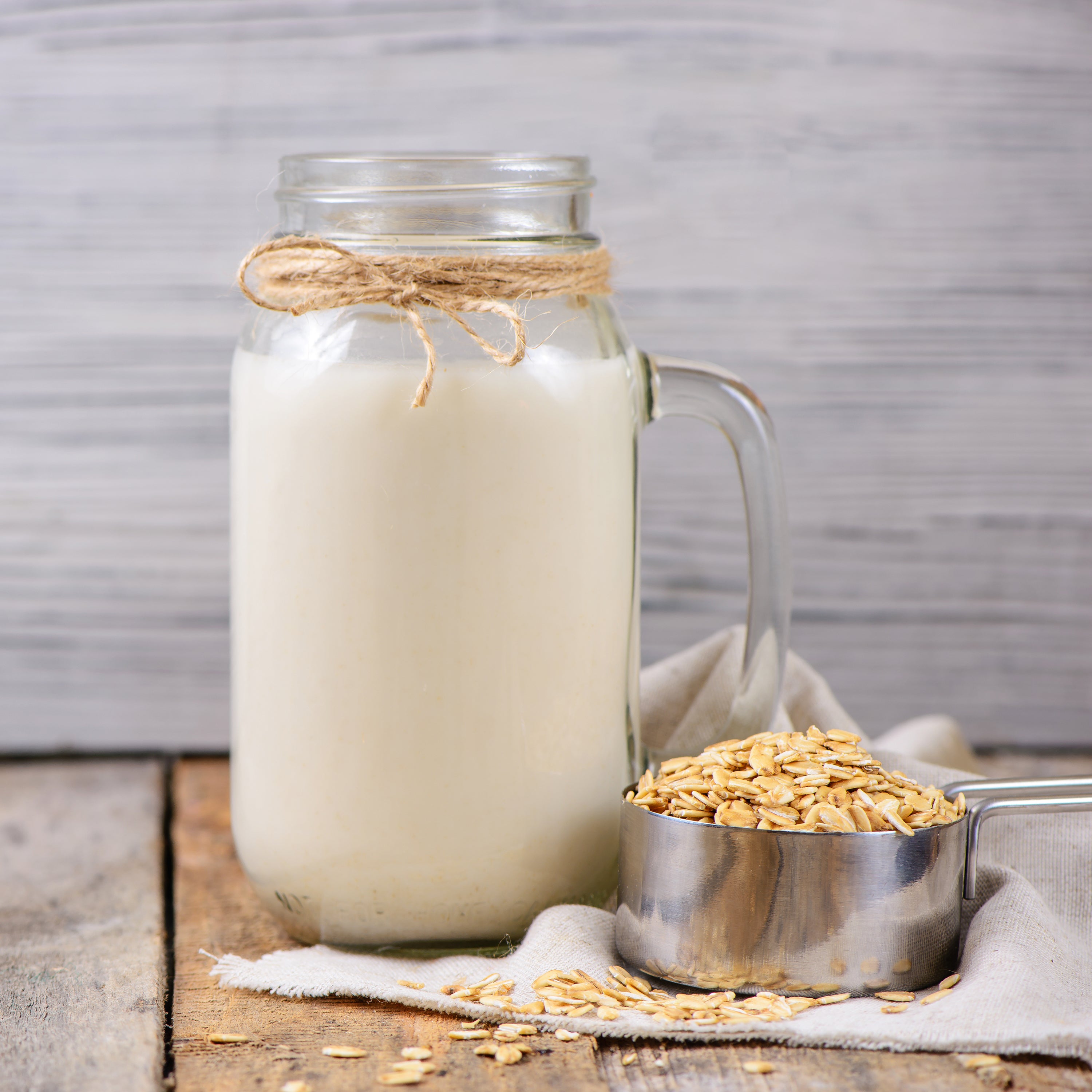 glass containers of oat milk and a measuring cup filled with oats