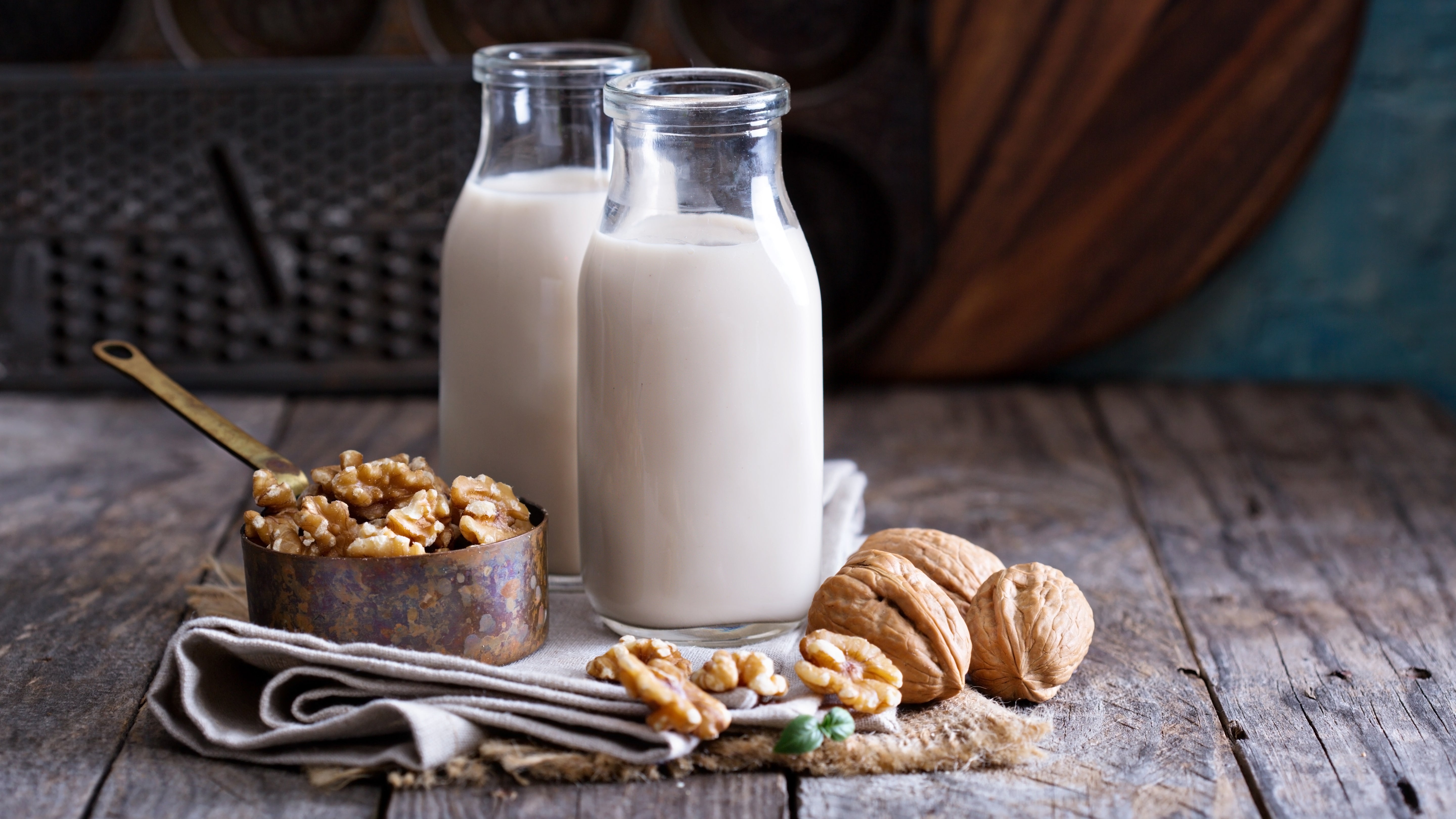 glass containers of walnut milk, walnuts and raw walnuts