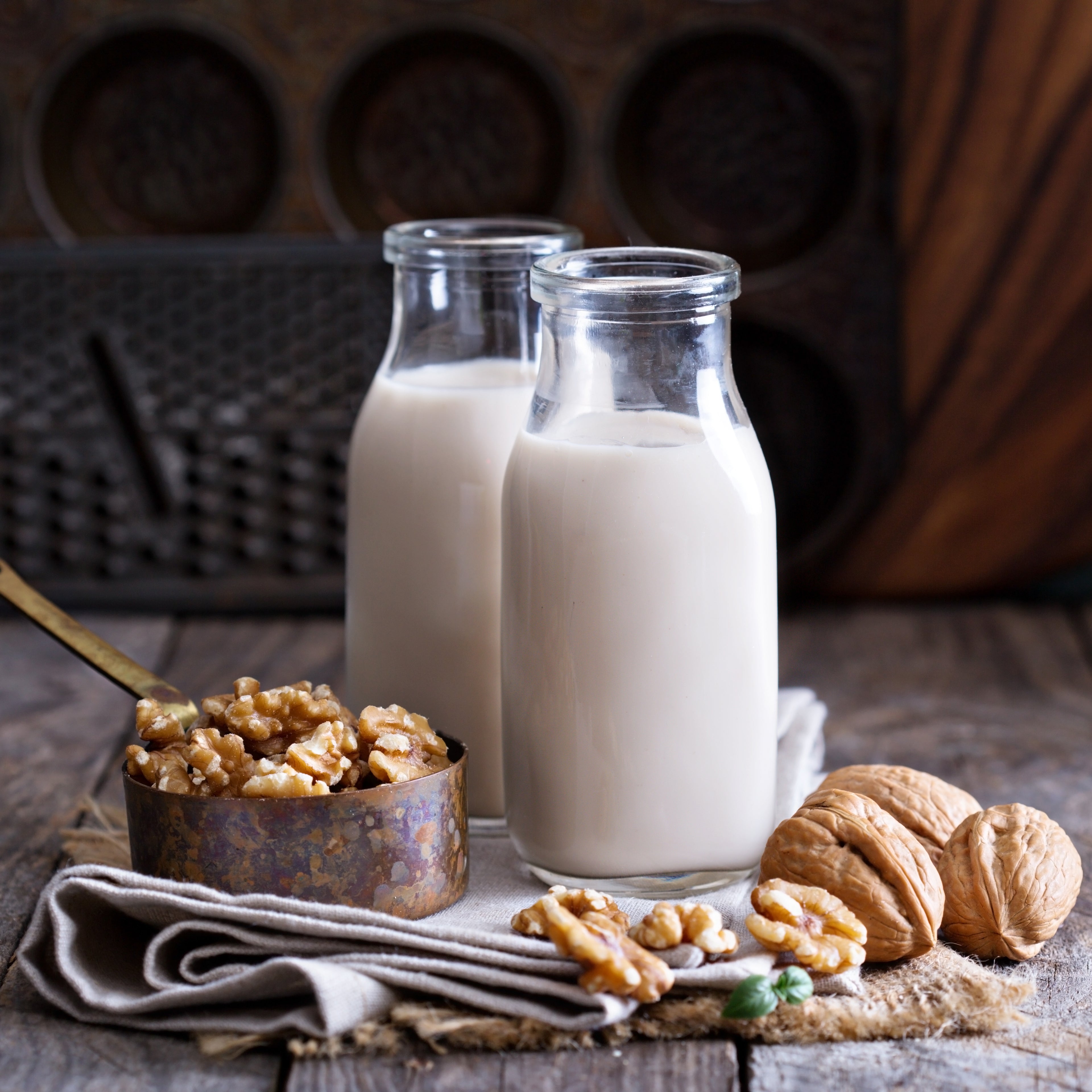 glass containers of walnut milk, walnuts and raw walnuts