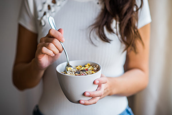 a woman eating a bowl of grains with oat milk