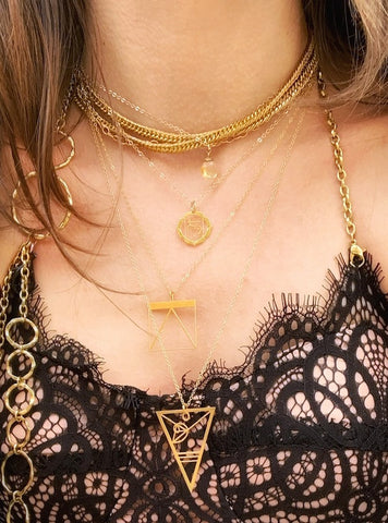 A model wears a black lacy top, gold chains, the Fibonacci necklace and a Chakra Pendant Necklace from Rael Cohen Jewelry