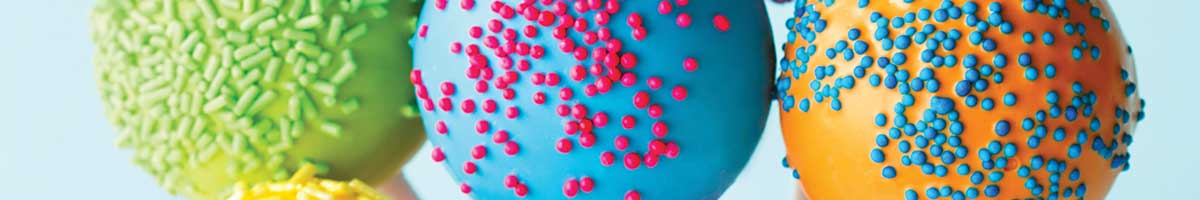 Three colorful round cake pops with sprinkles.