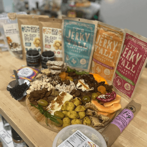 A vibrant charcuterie board featuring a variety of plant-based treats, paired with All Y'alls Foods vegan snack sampler packs, including jerky and snacks, creating a colorful vegan feast display.