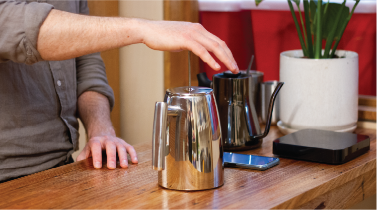 Hand pushing down on plunger whilst making French press (plunger) coffee